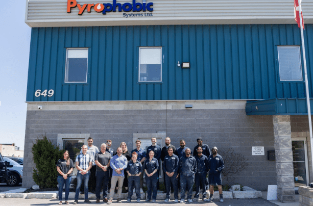 Pyrophobic Systems team members standing outside the company facility beneath the Pyrophobic Systems Ltd. sign.